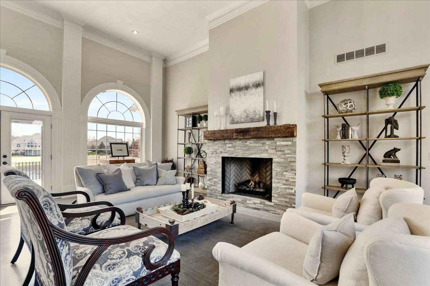 Longwood great room after renovation — stone fireplace, reclaimed wood mantel and arched windows