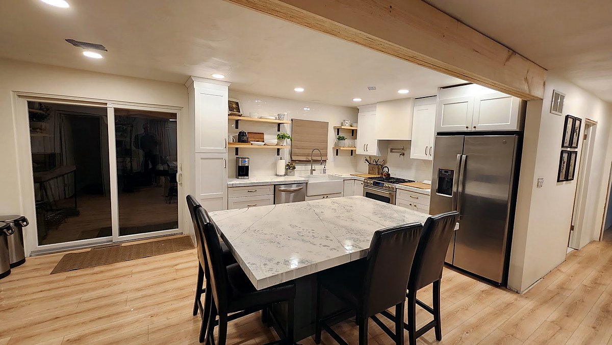 Roland home renovation after — open white kitchen with marble island and farmhouse sink